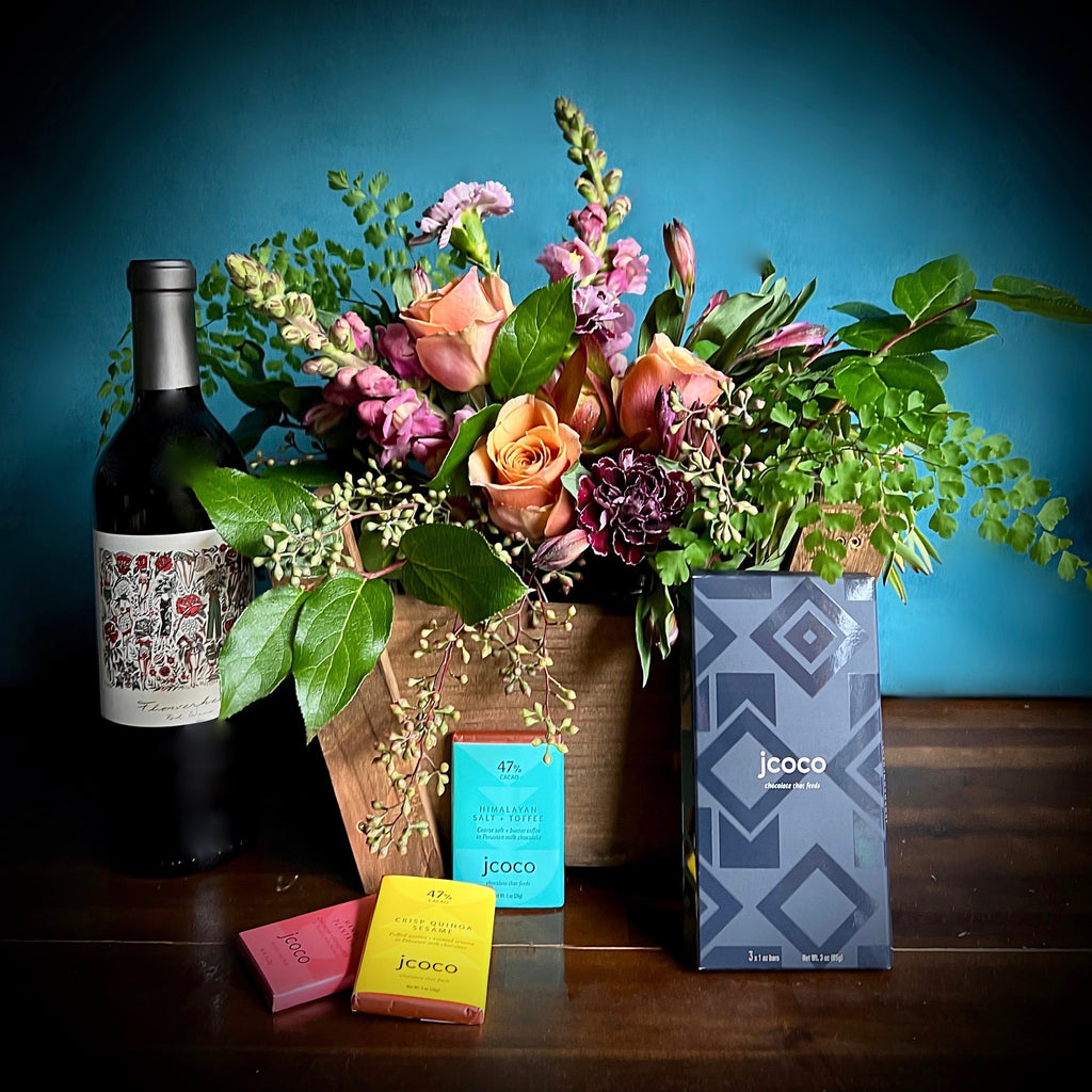 Wine & Chocolate - A beautifully seasonal floral designed in a wooden gift basket. Accompanied by a bottle of Mark Ryan Winery wine and Jcoco chocolates. Local delivery available. Perfect for a Mother's Day gift basket. 