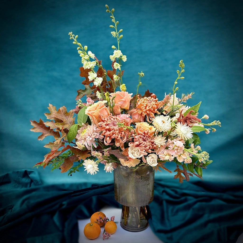 A soft and dreamy palette of peach, pink, soft orange, and creamy white in a glass pedestal vase. Designed by Seattle florist Campanula Design Studio located in Magnolia. A perfect Thanksgiving centerpiece.