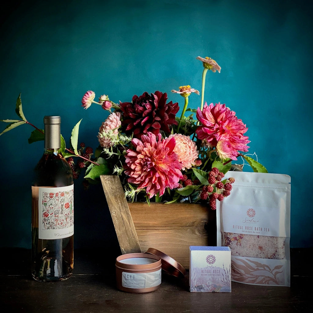The Rosé Garden gift basket from Campanula Design Studios in Seattle features A floral of beautifully colorful seasonal blooms designed in our petit panier basket, your choice of a bottle of TÖST non-alcoholic sparkling rosé beverage or a bottle of Mark Ryan Flowerhead Rosé, Sealuxe Rose Bath Tea, Sealuxe Ritual Rose Soap and a Sealuxe Rose Gold Candle
