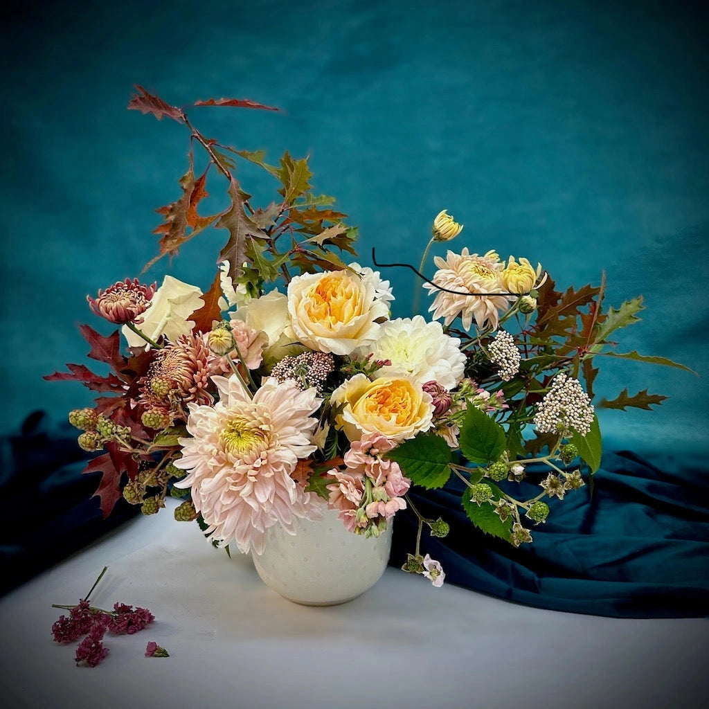 Campanula Design Studios presents "Allspice" - a holiday floral arrangment featuring pale blush, peach, soft yellows, and chocolatey red tones designed in a ceramic vase. Perfect as a Thanksgiving or Christmas centerpiece.