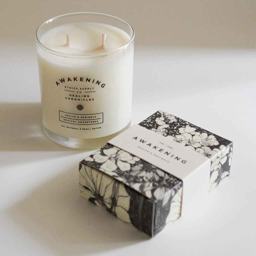 Candle and packaging with 'Awakening' branding on a light background
