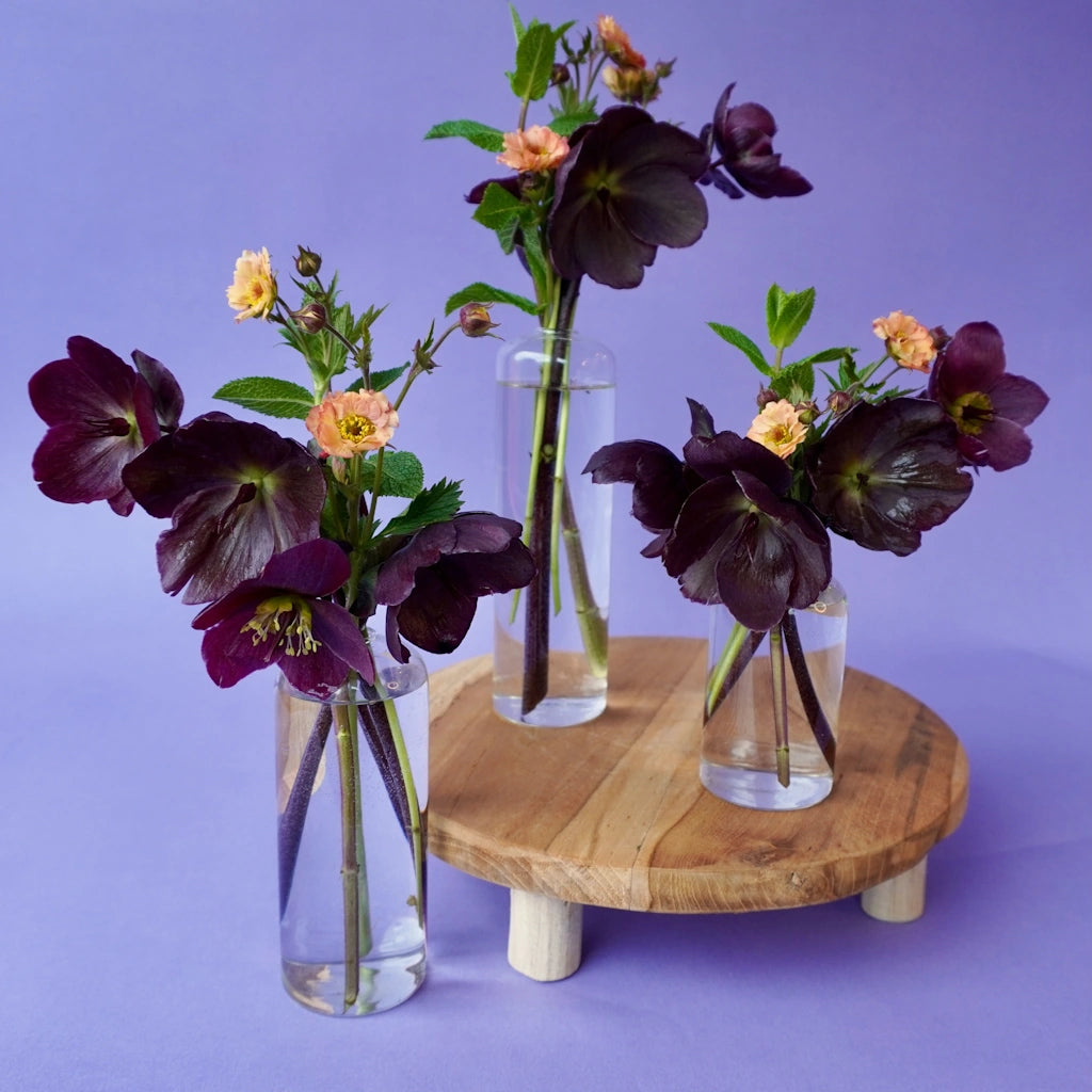 Three bud vases with purple flowers on a lavender background - Available as wedding table decorations from Campanula Design Studio, Seattle florist and gift basket company.