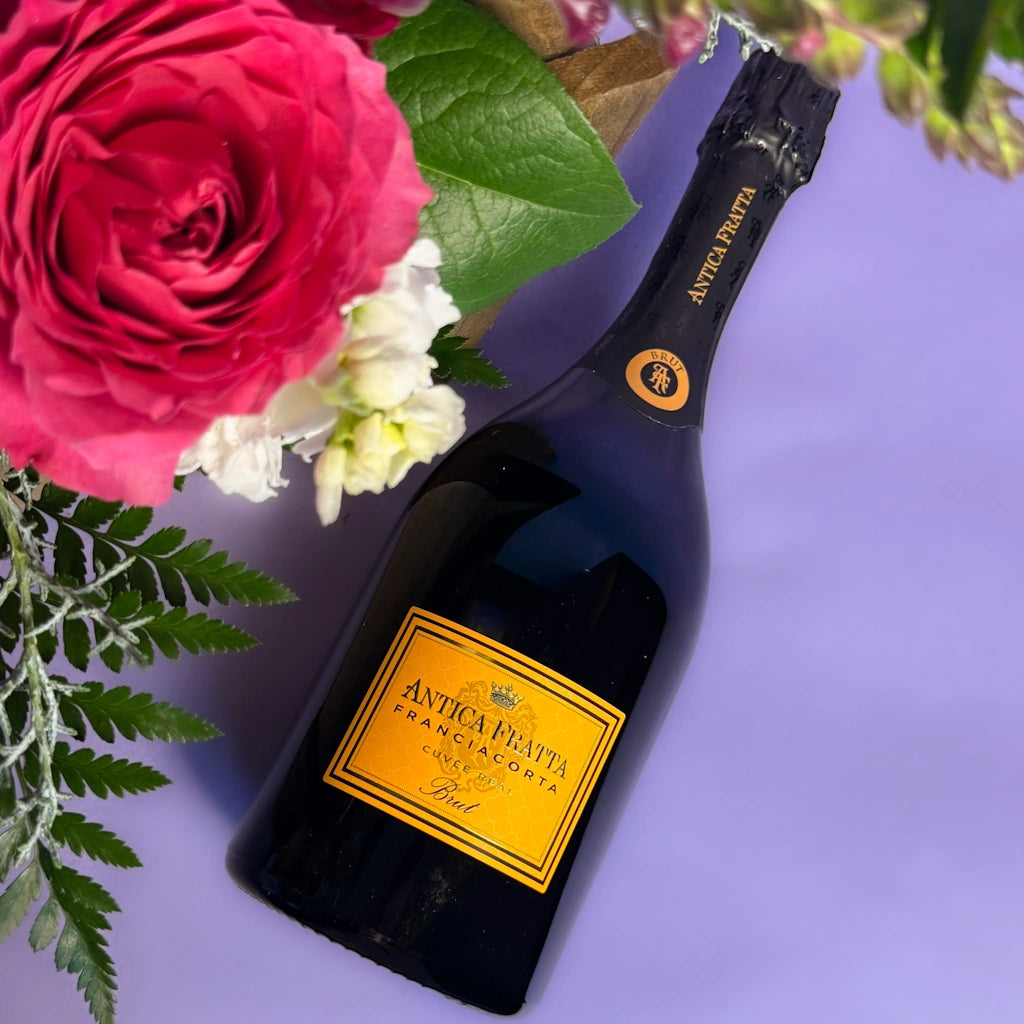 Bottle of Antica Fratta champagne with flowers on a purple background