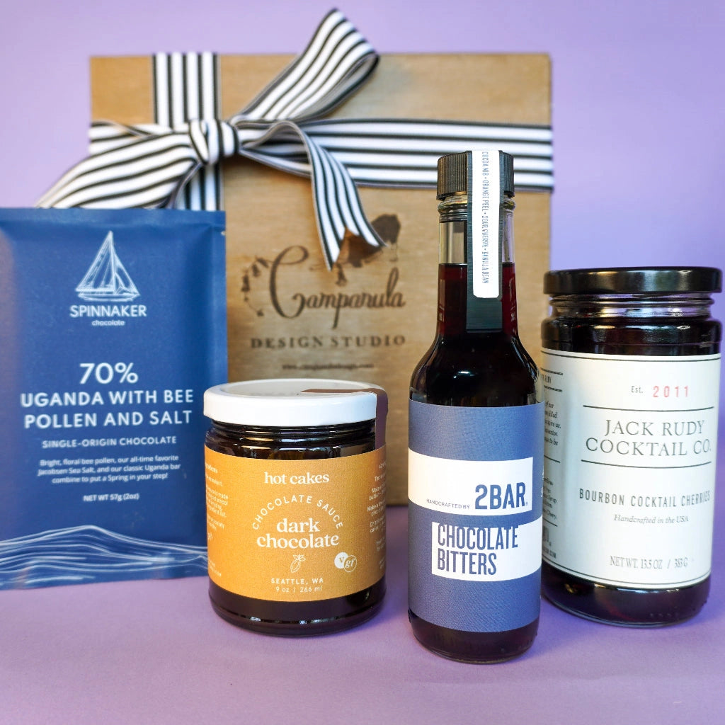 Gift box for nationwide US shipping with Spinnaker chocolate, 2Bar chocolate bitters, hotcakes dark chocolate sauce and bourbon soaked cocktail cherries. Available from Campanula Design Studio, Seattle florist and gift basket company in Magnolia.