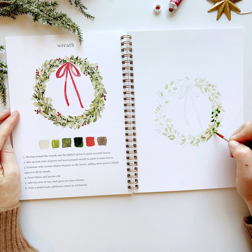 Open book with a wreath illustration and color swatches, hands holding the book.  Available for sale from Campanula Design Studio, Seattle florist and gift basket company in the Magnolia neighborhood.
