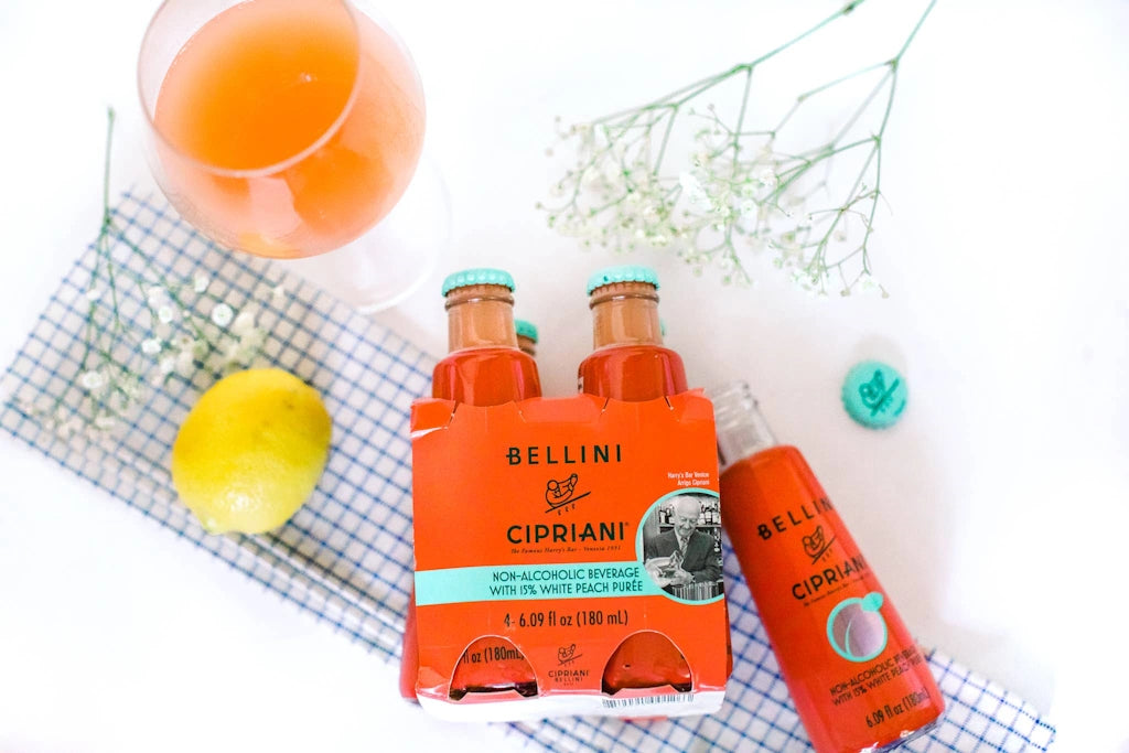 Bellini Cipriani bottles with a glass of orange juice and lemon on a checkered cloth.