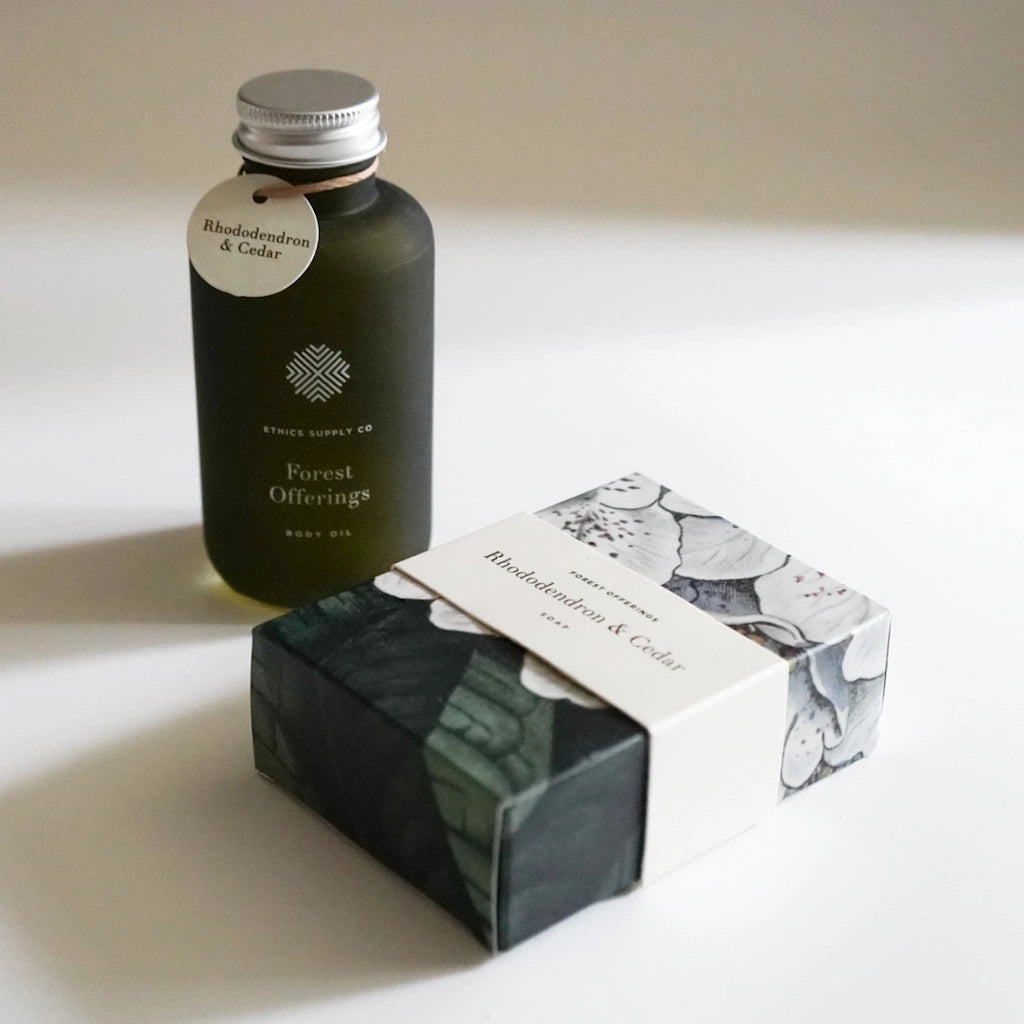 Bottle of 'Forest Offering' body oil with packaging on a light background