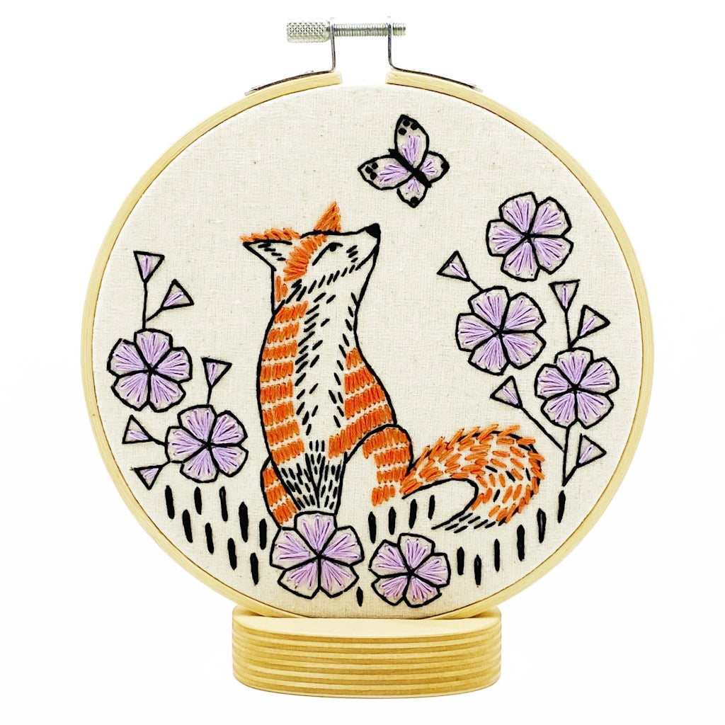 Embroidery hoop with a fox and floral design on a white background