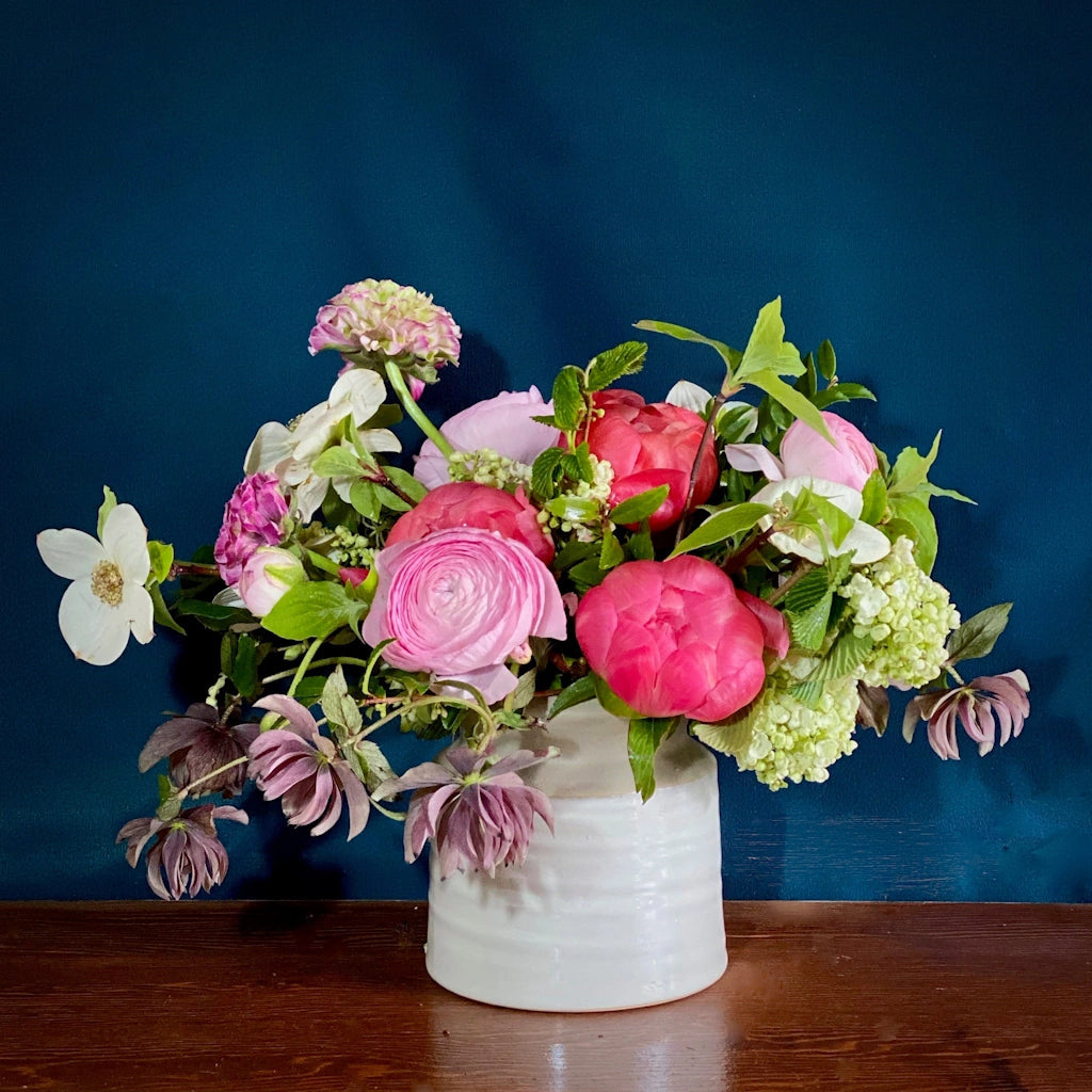 A mix of seasonal blooms designed in a ceramic vase. 