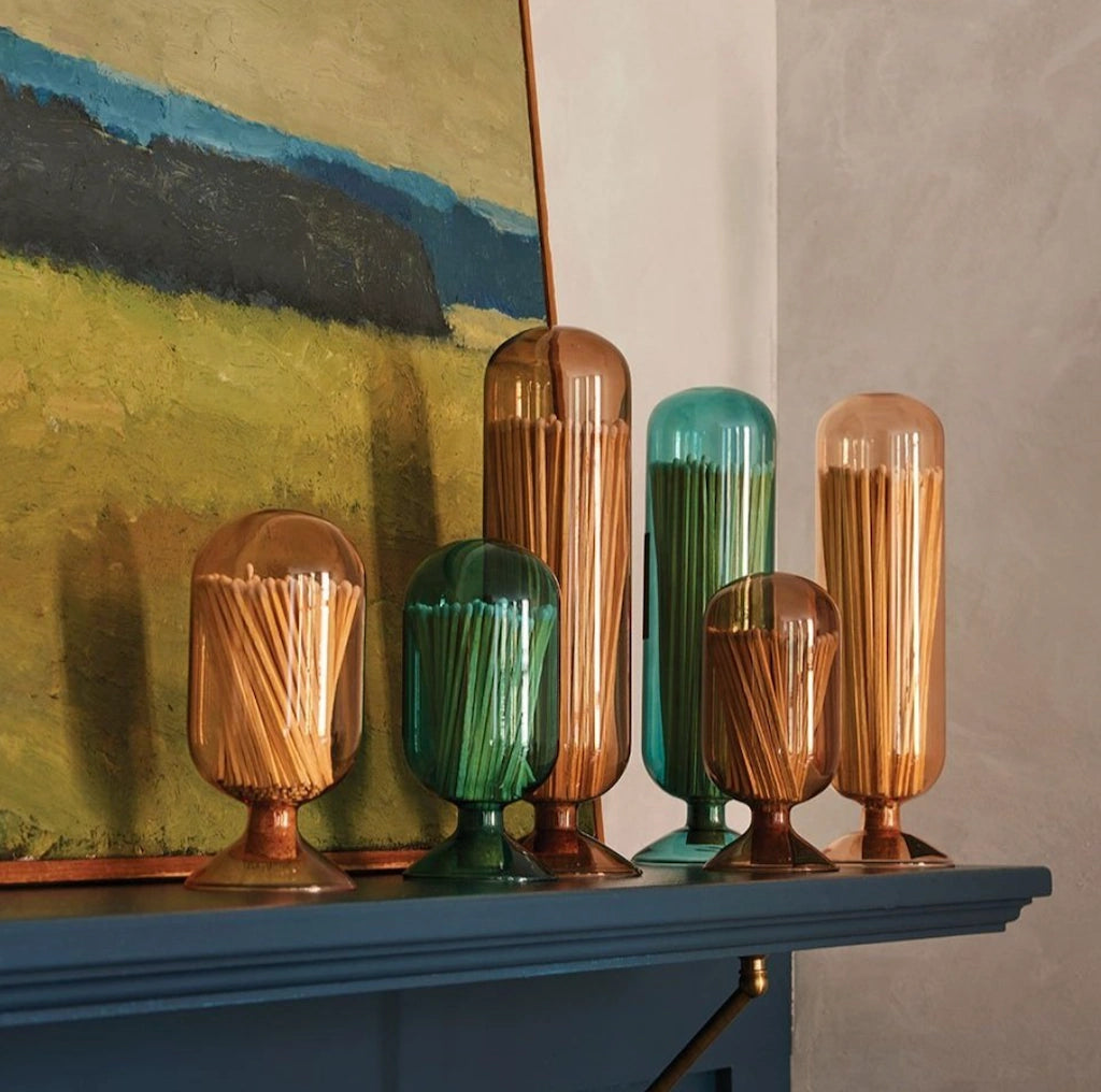 From Campanula Design Studio: Inspired by vintage glass domes used to protect seedlings, these Match Cloches are made of handblown glass and fitted with a cork to shold an assortment of matchsticks. A striker flint on the glass adds functionality. Choose from apricot or teal glass. 