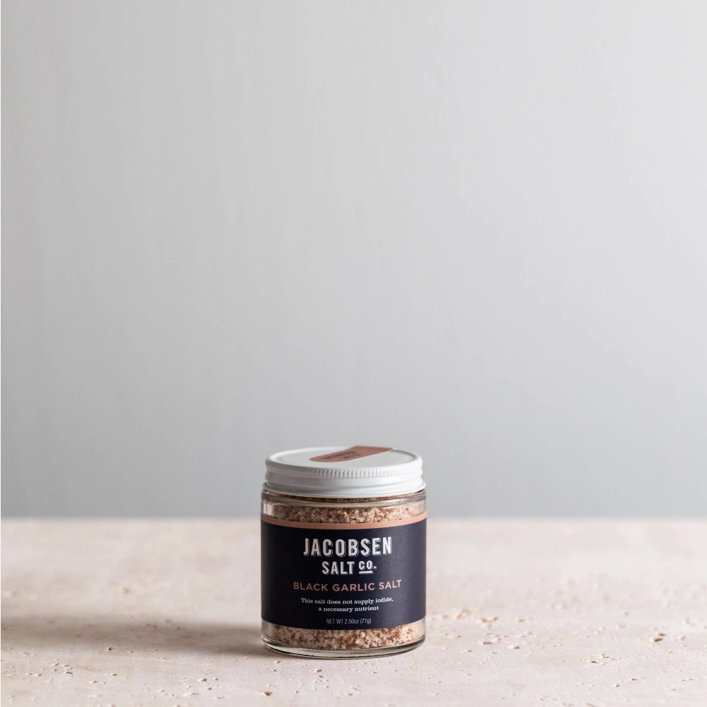 Jar of Jacobsen Salt Co. black garlic salt on a light surface with a gray background