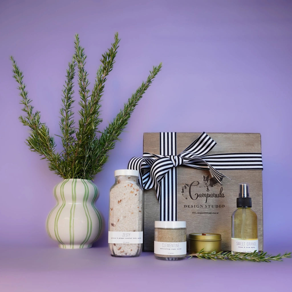 Set of skincare products and a gift box with a bow on a purple background. Available from Campanula Design Studio, Seattle florist and gift basket company in Magnolia.