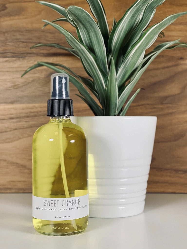 Bottle of Sweet Orange linen and room spray with a plant in the background