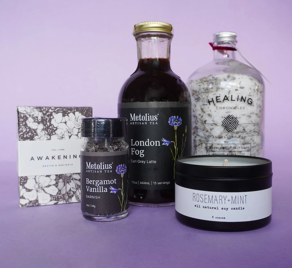 Collection of Metolius tea, Healing Chronicles product, and candles on a purple background.  Available for sale from Campanula Design Studio, Seattle florist and gift basket company in the Magnolia neighborhood.