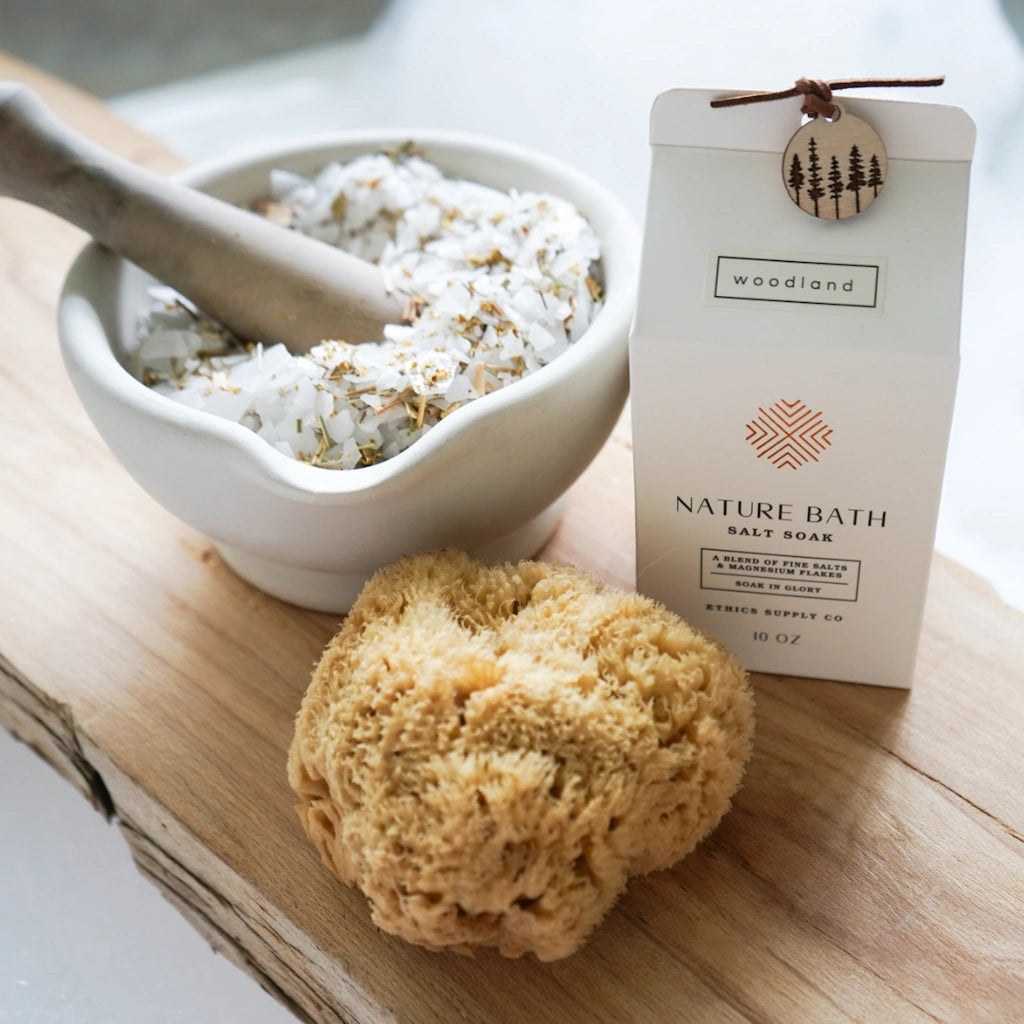 Nature Bath salt soak with a loofah and wooden pestle on a wooden surface