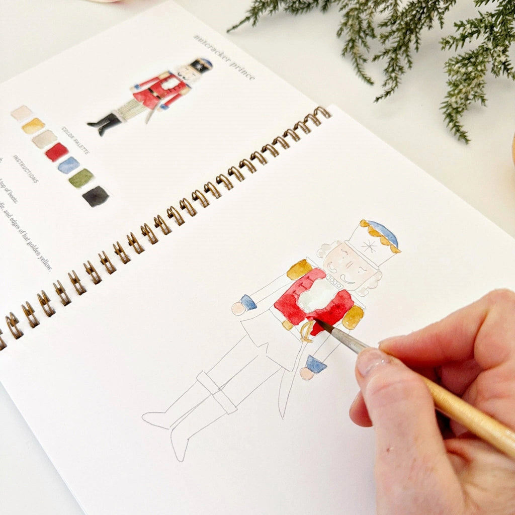 Person coloring a nutcracker illustration in a sketchbook with a color swatch nearby.
