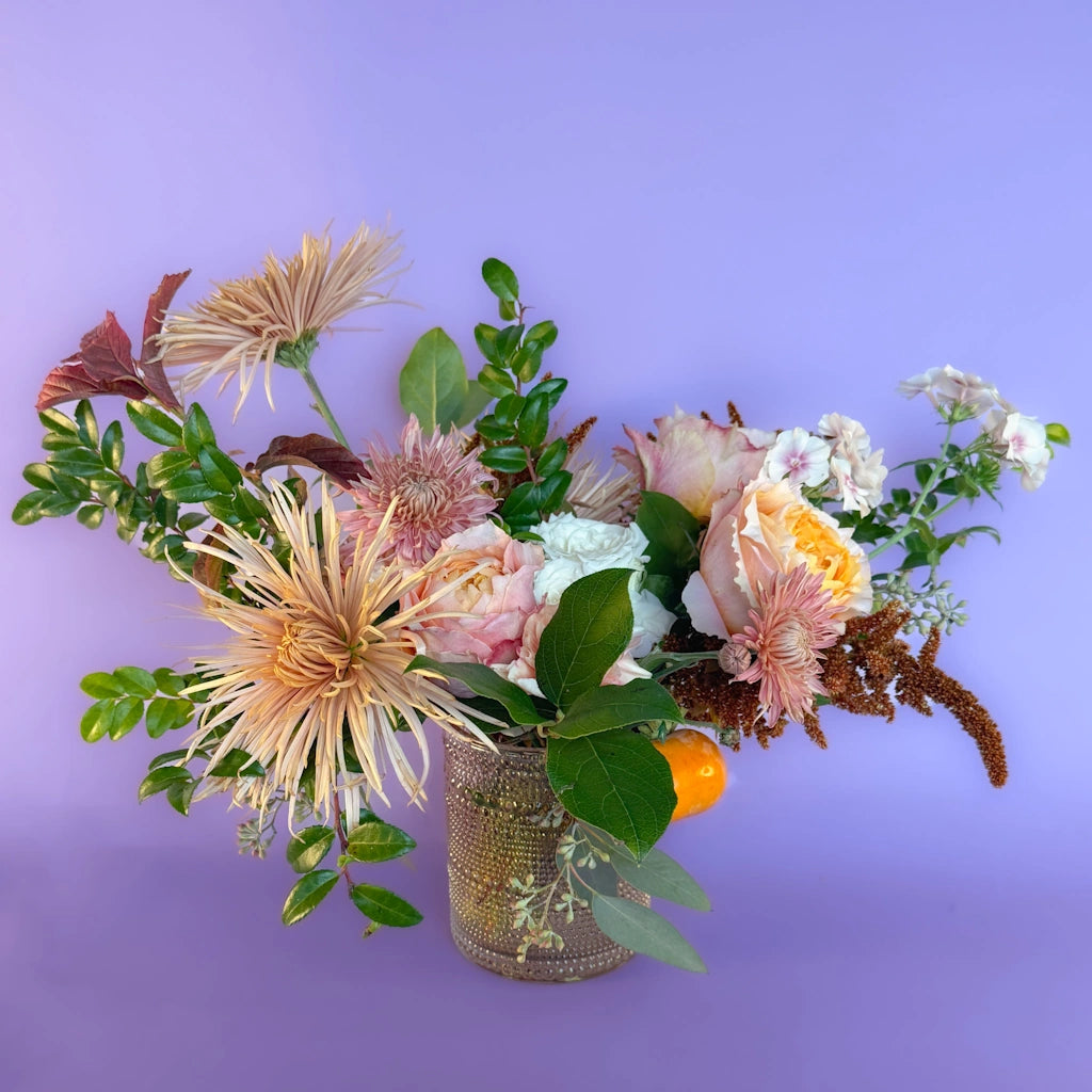 Bouquet of flowers named "Peach Cobbler" in a vase on a purple background