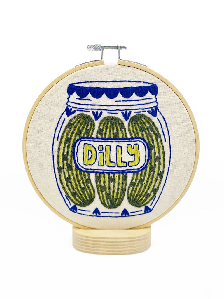 Embroidery hoop with a jar of pickles design and 'Dilly' text on a white background