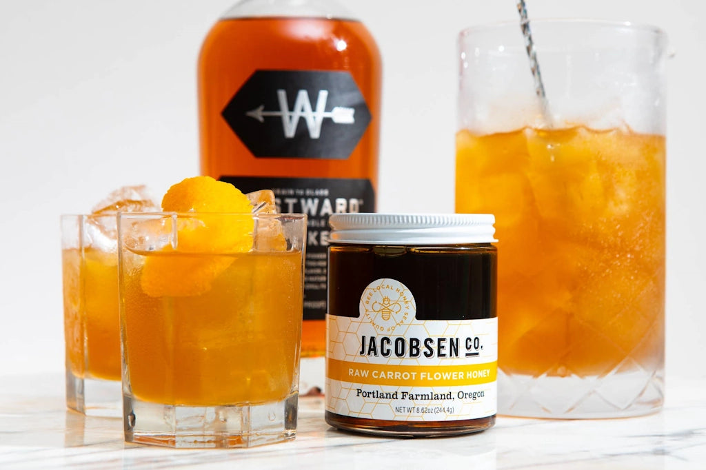 Beverages with a jar of Jacobsen raw carrot honey on a white background