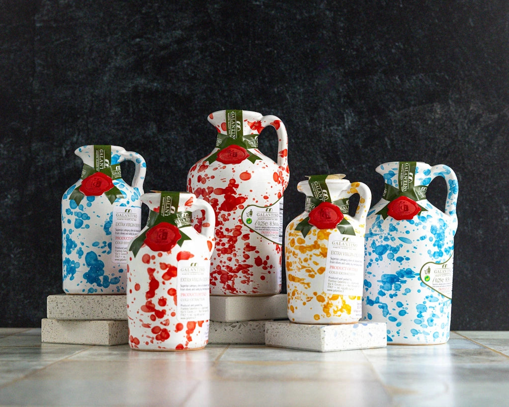 Set of colorful ceramic jugs of olive oil with floral designs on a dark background