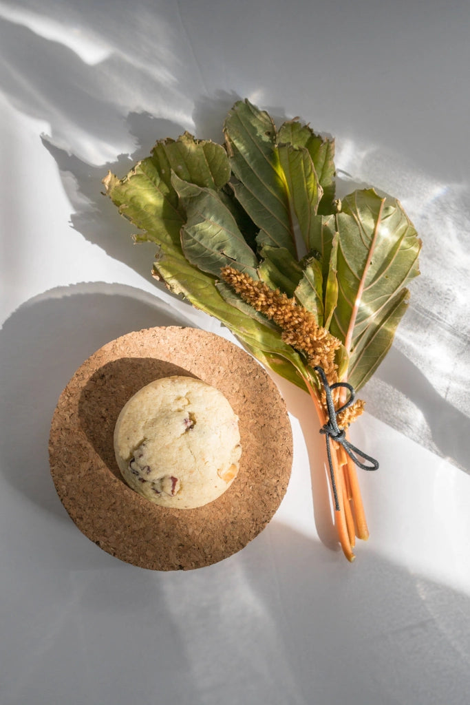 Cork bowl with a shortbread cookie and green leaves on a white surface