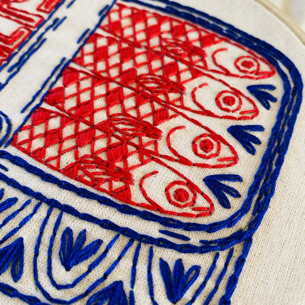 Embroidery with red and blue fish design on a white background