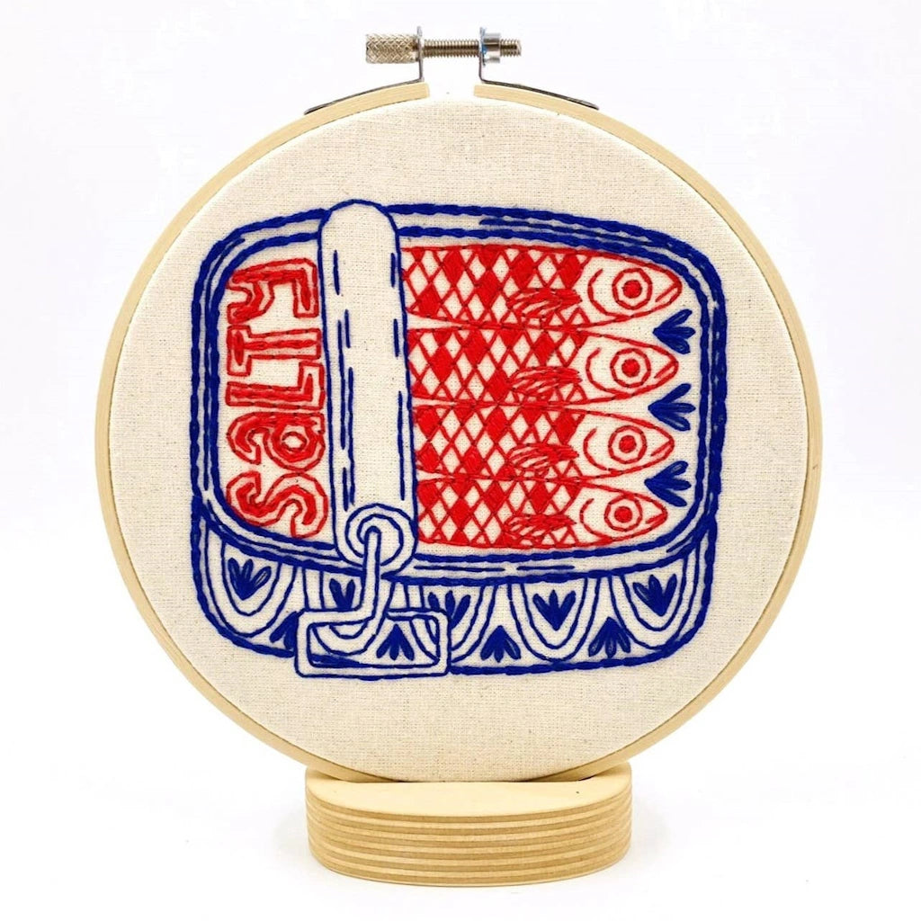 Embroidery hoop with red and blue fish pattern on a white background