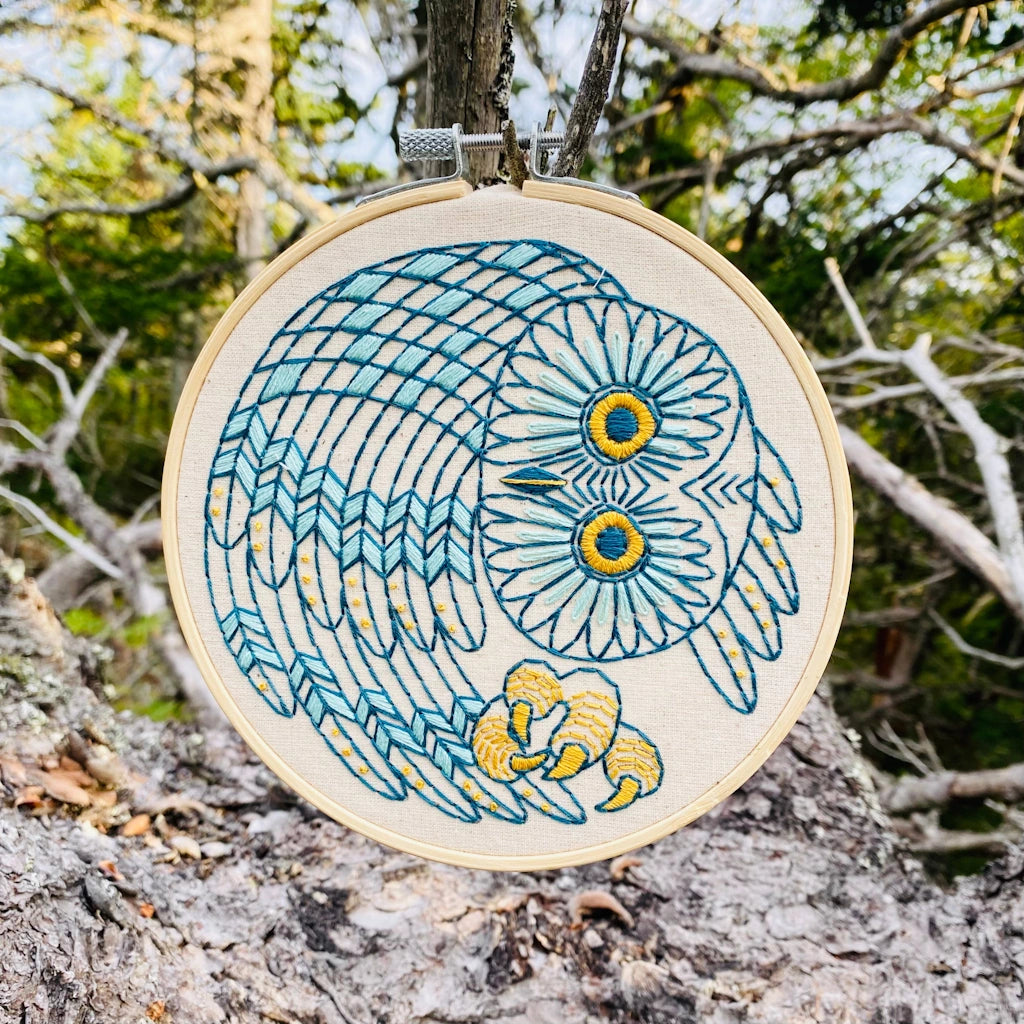 Embroidery hoop with owl design hanging on a tree branch