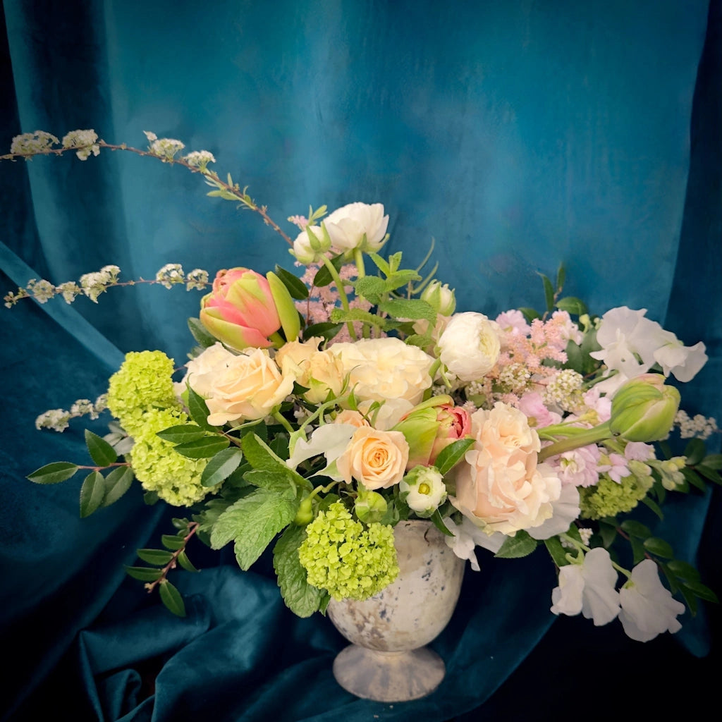 The Serenity floral arrangement from Campanula Design features a soft and soothing palette of pale pink, peach, white, and lush greens designed in a simple vase.