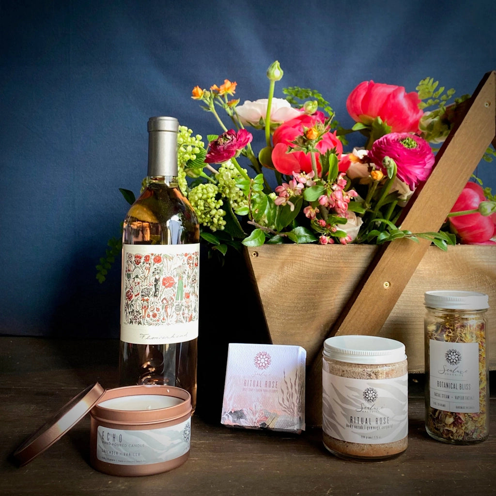 Campanula Design's "Spa Day" gift basket includes: A seasonal floral, Travel tin candle, Sealuxe rose body scrub (rose bath tea, body butter or bath salt may be substituted if unavailable), Sealuxe Rose Ritual soap, Sealuxe Botanical Bliss Steam Facial, A bottle of TÖST non-alcoholic sparkling rosé beverage or a bottle of wine. 