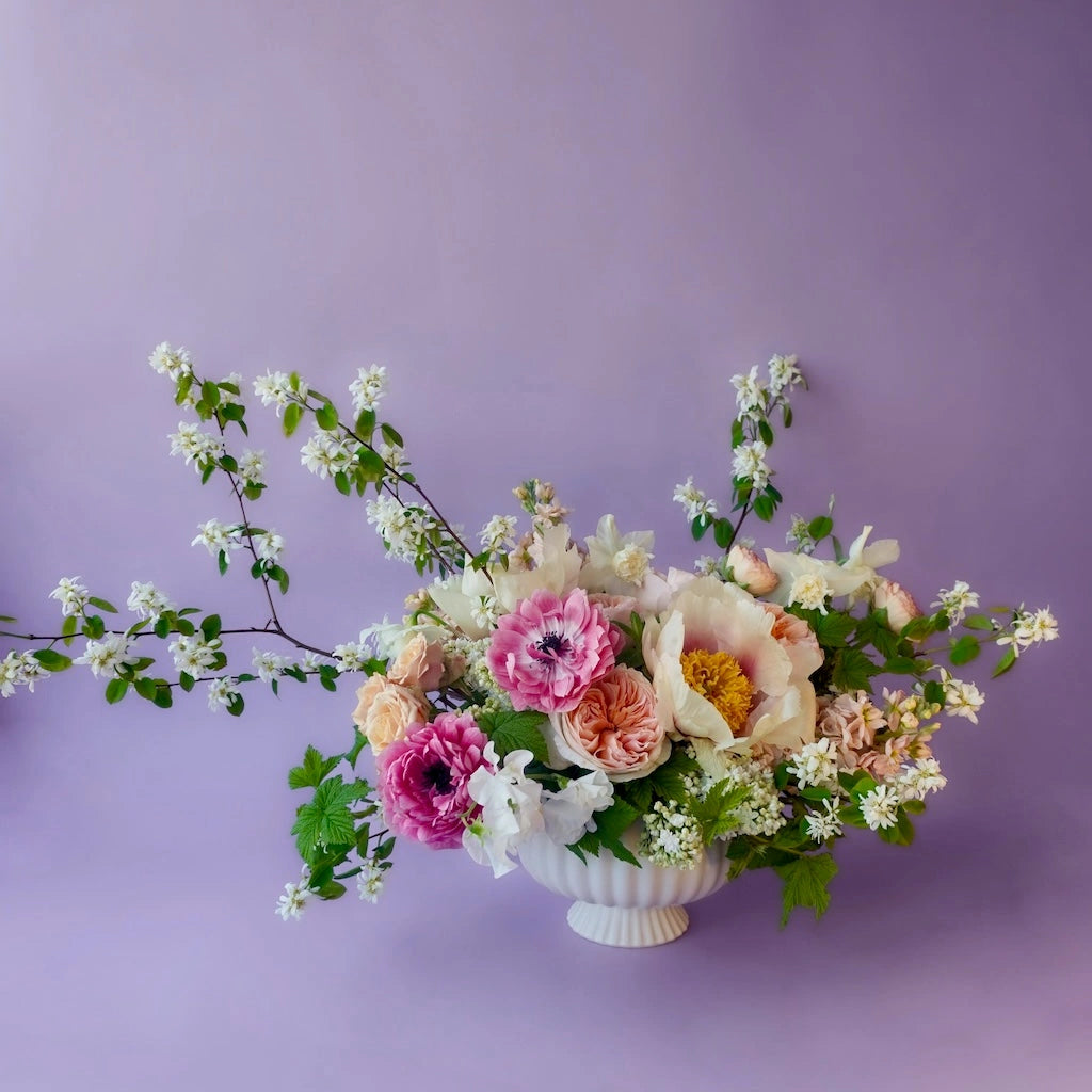 Wedding statement piece Floral arrangement in a white vase against a purple background. Available from Campanula Design Studio, Seattle florist and gift basket company.