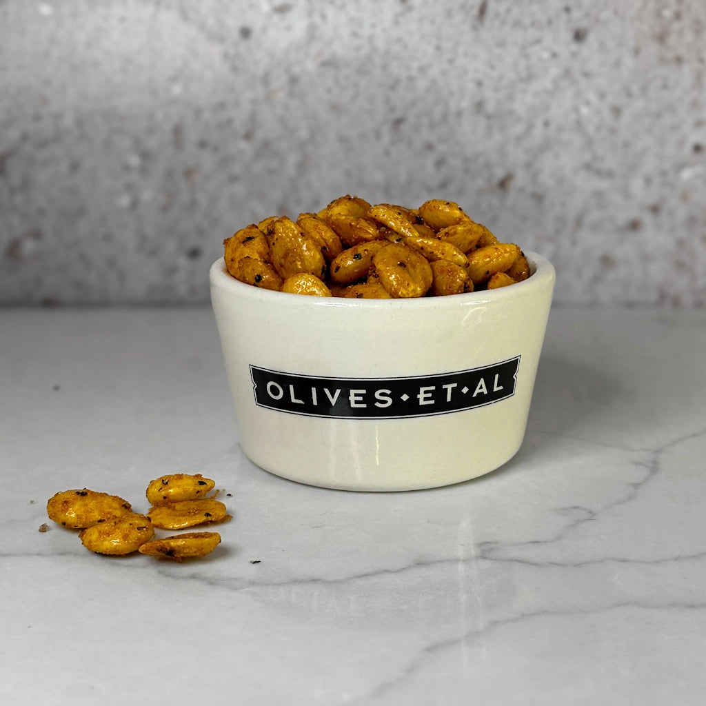 White bowl of Marcona Sweet Paprika Almonds with a visible label on a gray background available from Seattle florist and gift basket company, Campanula Design Studio in Magnolia