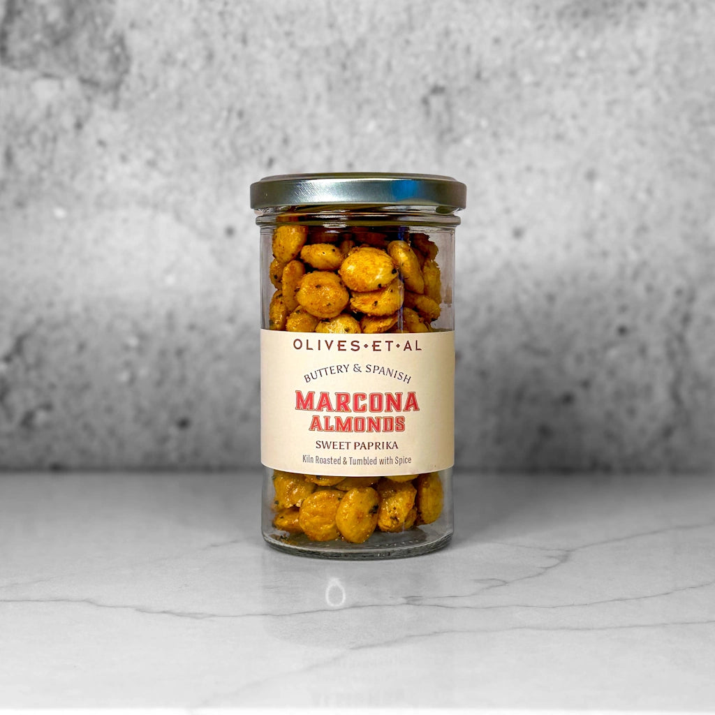 Jar of Marcona Sweet Paprika Almonds with a visible label on a gray background available from Seattle florist and gift basket company, Campanula Design Studio in Magnolia