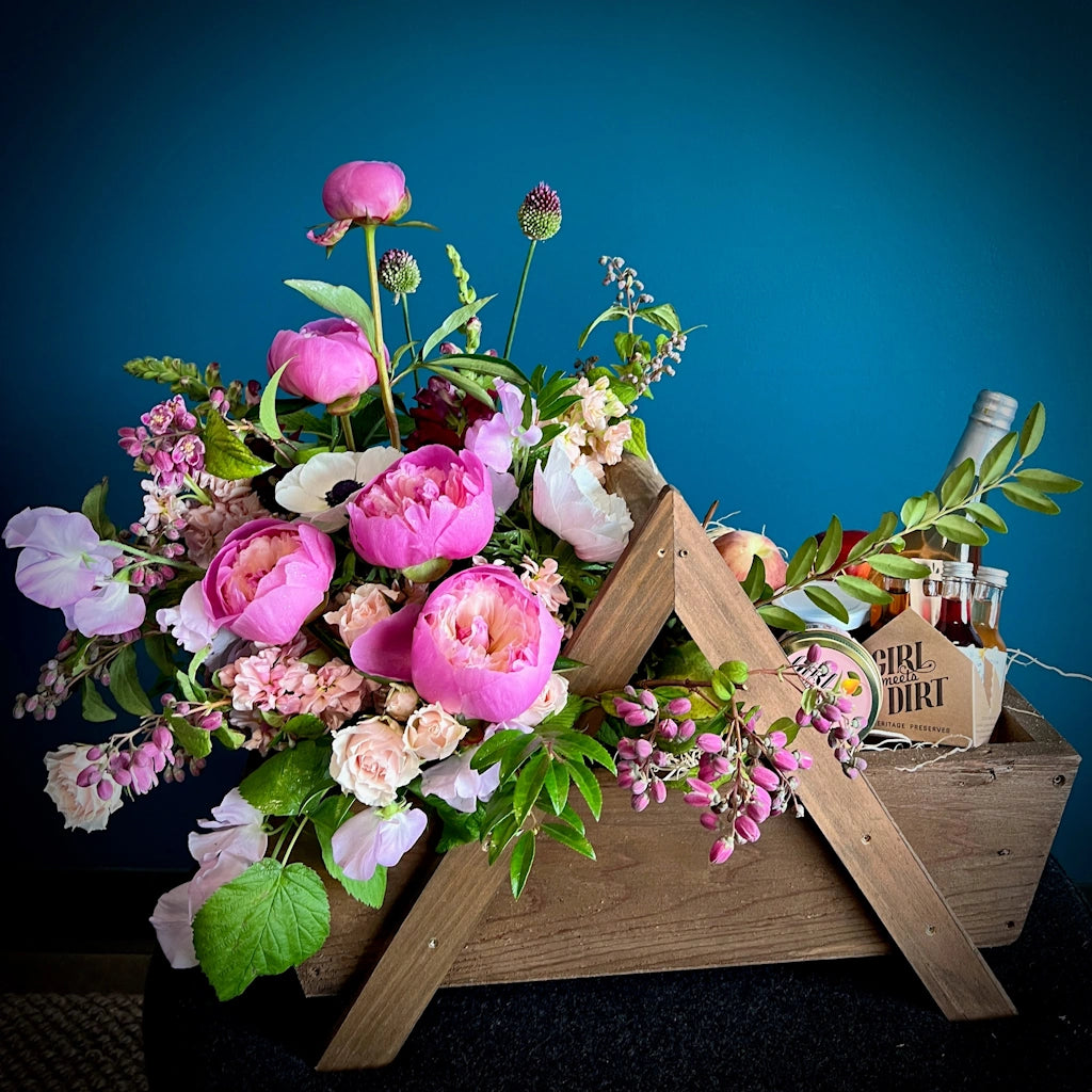 A custom gift basket by Seattle Florist Campanula Design Studio. Designed in our handmade wooden gift basket, this beauty includes a floral of locally grown seasonal blooms, a selection of Girl Meets Dirt products, and a bottle of TÖST, a non-alcoholic sparkling tea. Available for same day local delivery throughout the Greater Seattle area.