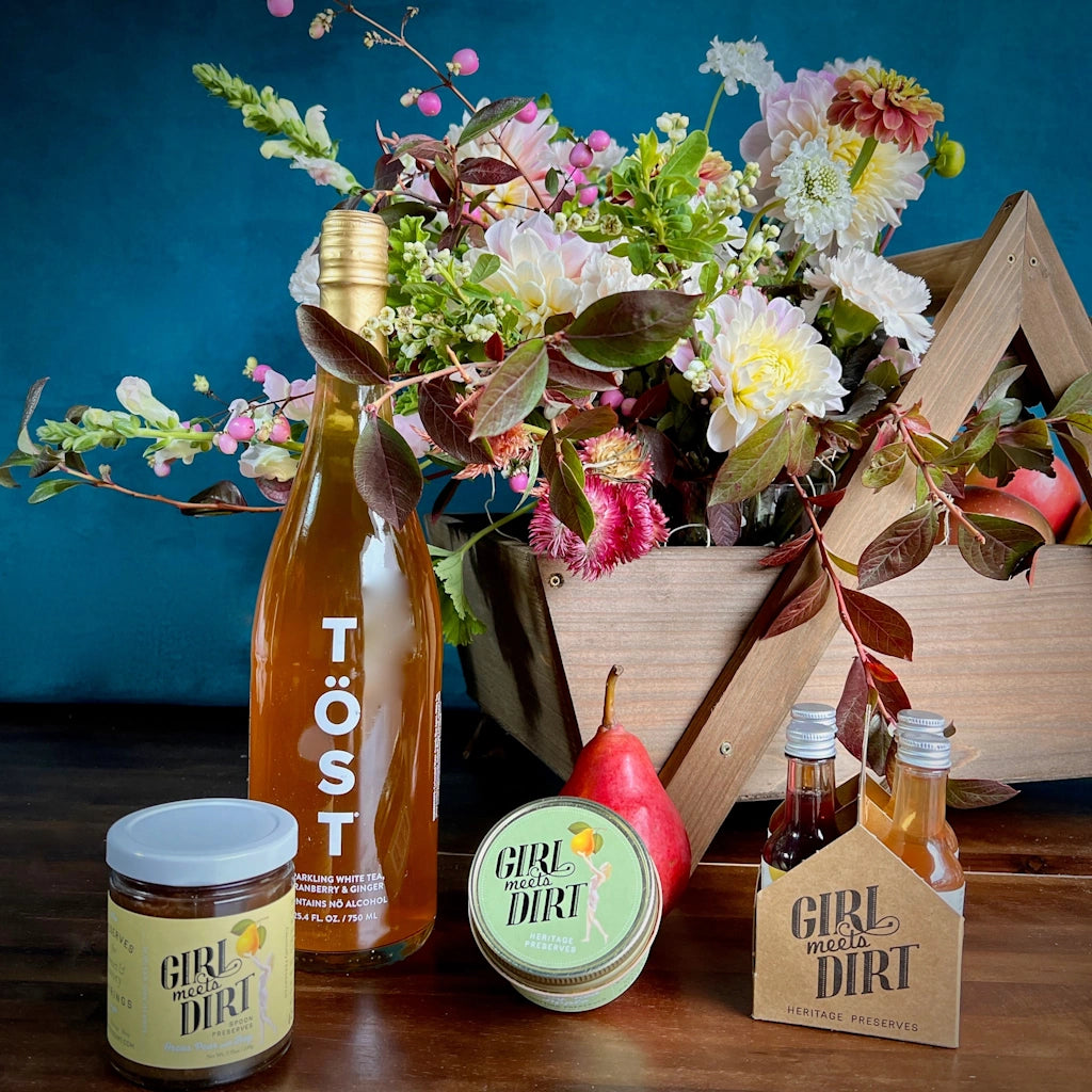 A custom gift basket by Seattle Florist Campanula Design Studio. Designed in our handmade wooden gift basket, this beauty includes a floral of locally grown seasonal blooms, a selection of Girl Meets Dirt products, and a bottle of TÖST, a non-alcoholic sparkling tea. Available for same day local delivery throughout the Greater Seattle area.