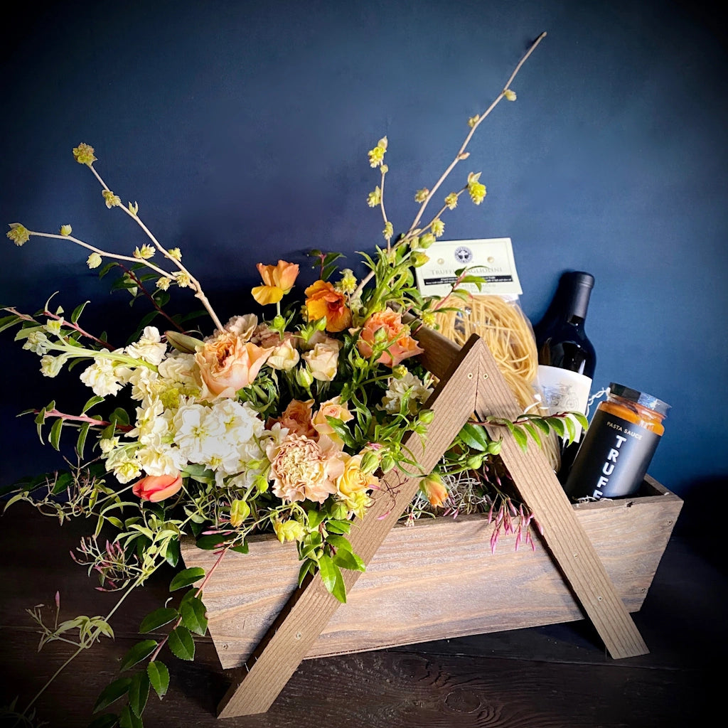 A custom gift basket of locally grown flowers, truffle flavored items such as olives, TRUFF pasta sauce, and truffle pasta accompanied by a bottle of Mark Ryan Winery wine. Designed by Seattle gift basket company Campanula Design Studio, this item is available for local Seattle delivery.