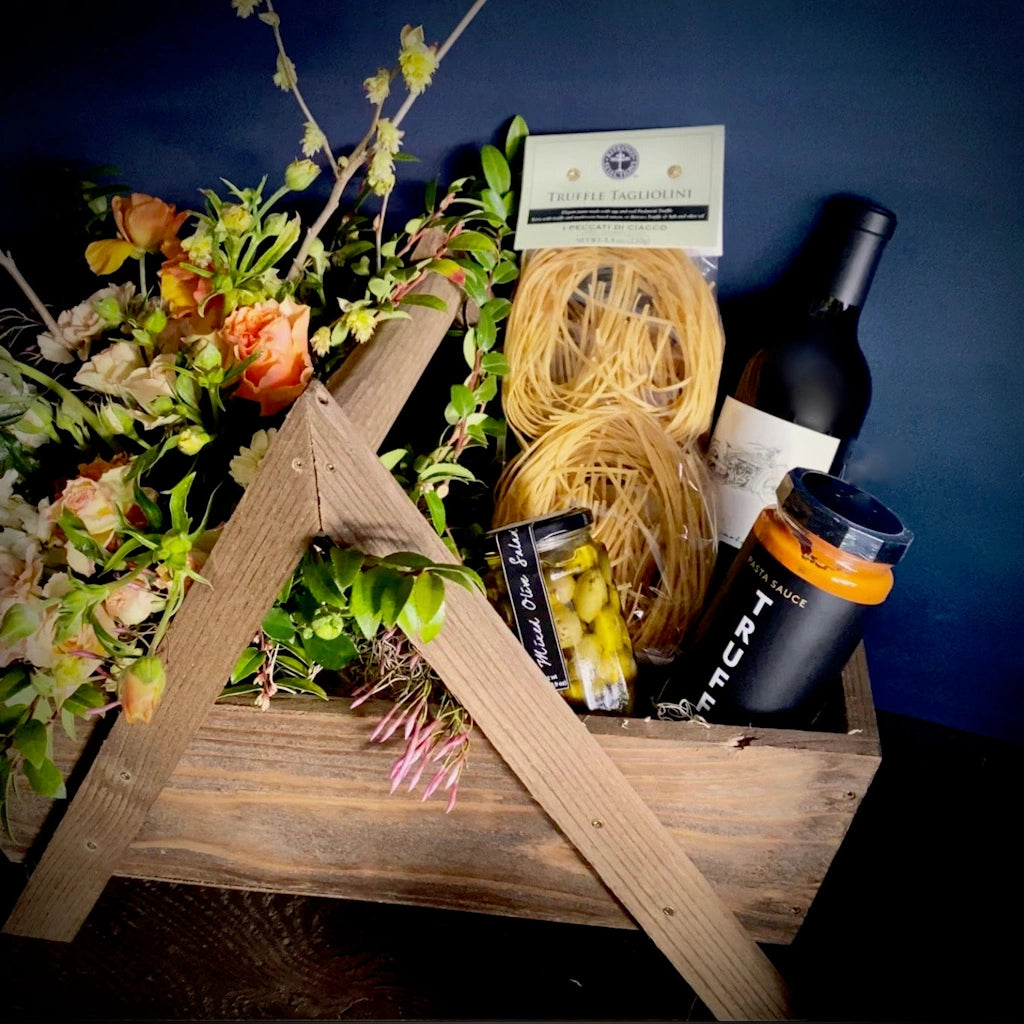 A custom gift basket of locally grown flowers, truffle flavored items such as olives, TRUFF pasta sauce, and truffle pasta accompanied by a bottle of Mark Ryan Winery wine. Designed by Seattle gift basket company Campanula Design Studio, this item is available for local Seattle delivery.