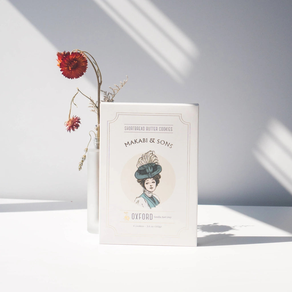 Book titled 'Makabi & Sons' with a decorative vase of flowers on a light background