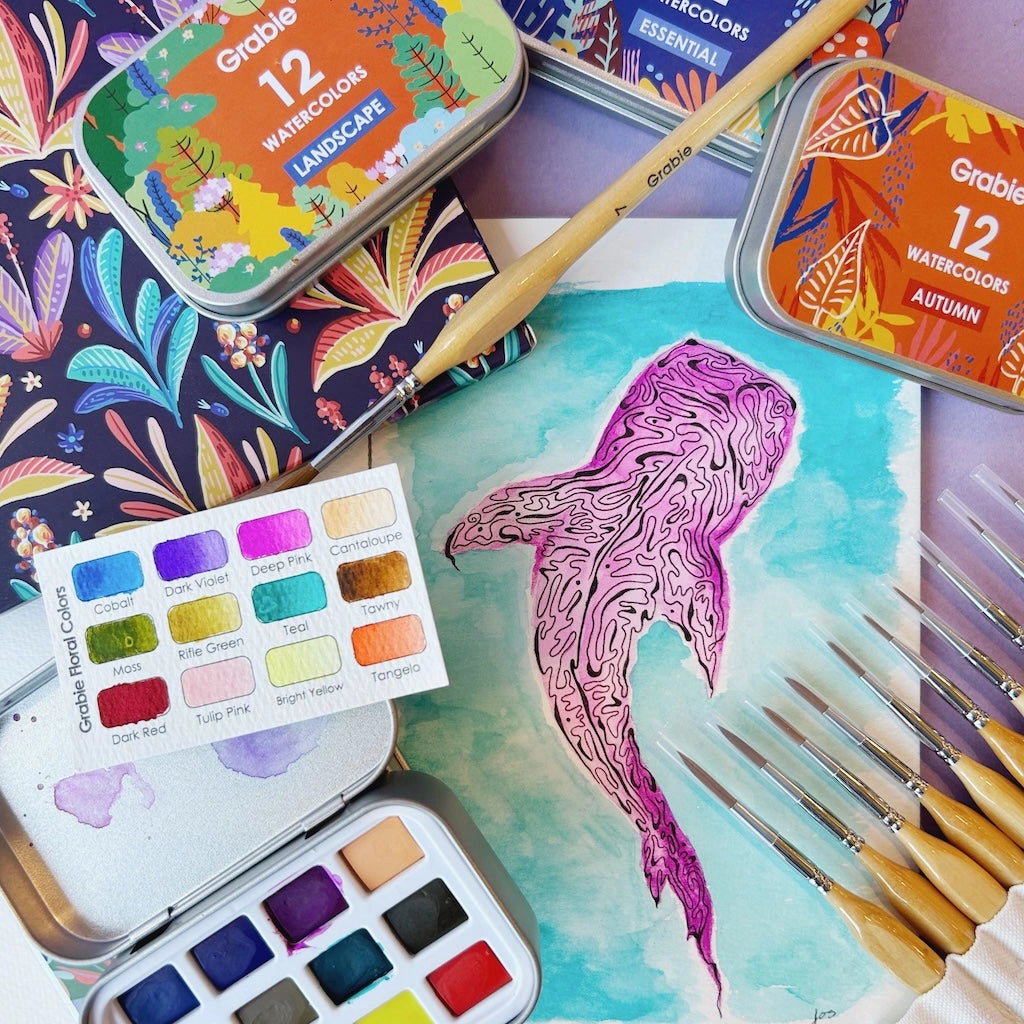 Colorful watercolor set with a painted whale, paintbrushes, and color swatches on a decorative background.